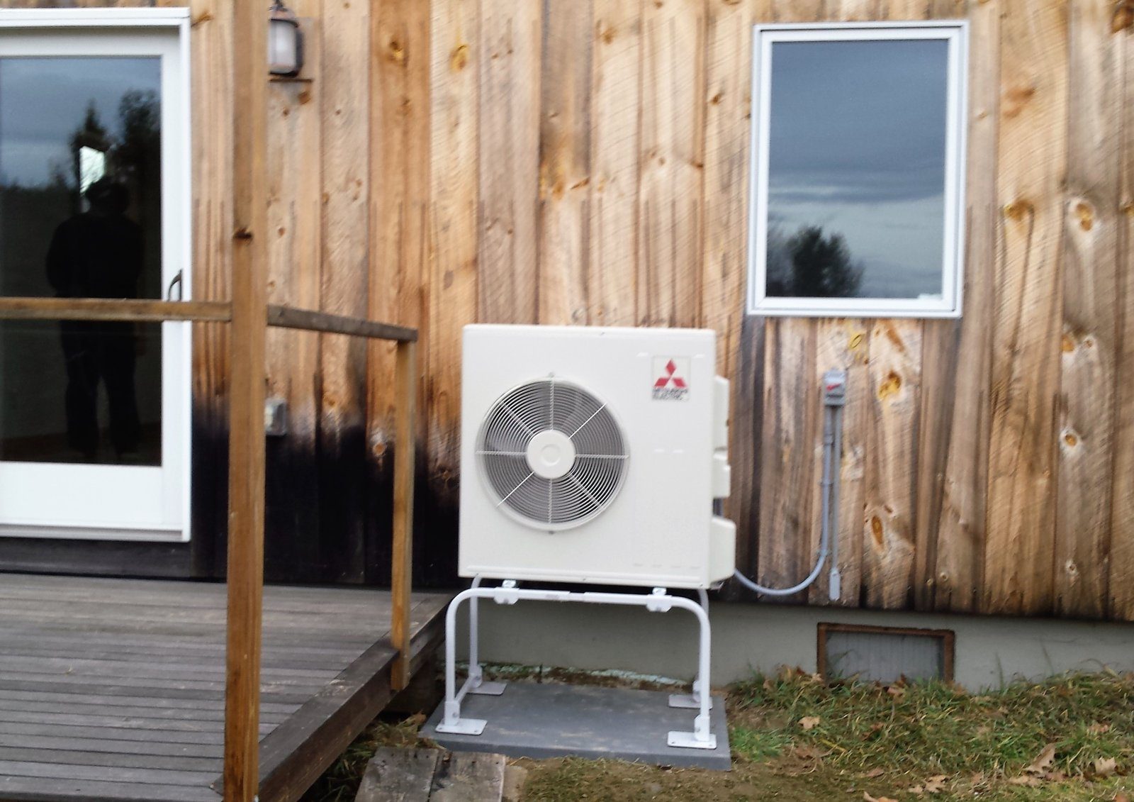 Mitsubishi ductless heat pump outdoor unit mounted on a wood fence